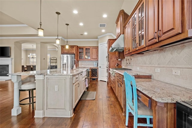 kitchen featuring light stone countertops, a breakfast bar area, ventilation hood, and a center island with sink