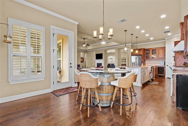 dining room with ornamental molding, dark hardwood / wood-style floors, and ceiling fan with notable chandelier