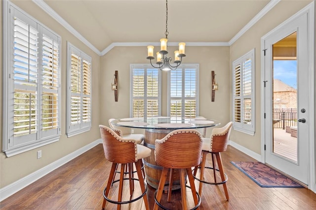 dining space with ornamental molding, hardwood / wood-style floors, and a notable chandelier