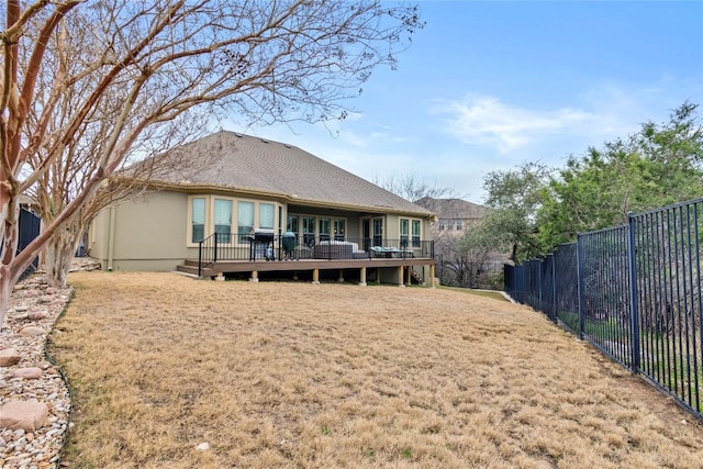 rear view of house with a wooden deck and a lawn