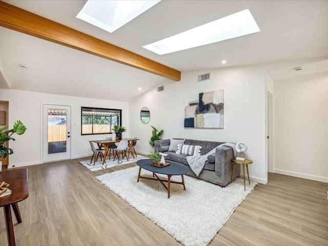 living room featuring vaulted ceiling with skylight and light hardwood / wood-style floors