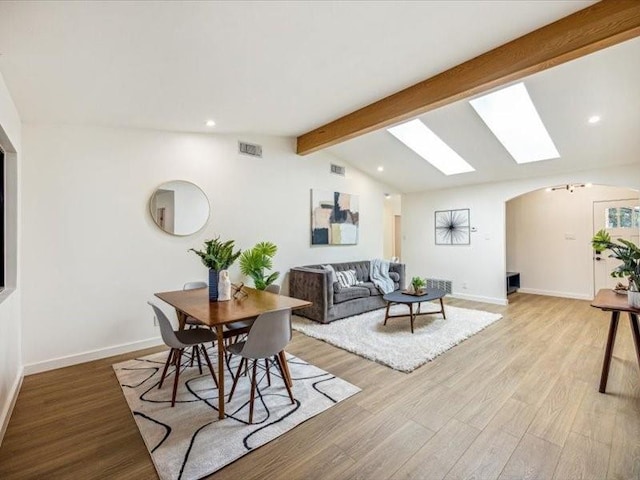 living room with vaulted ceiling with skylight and light wood-type flooring