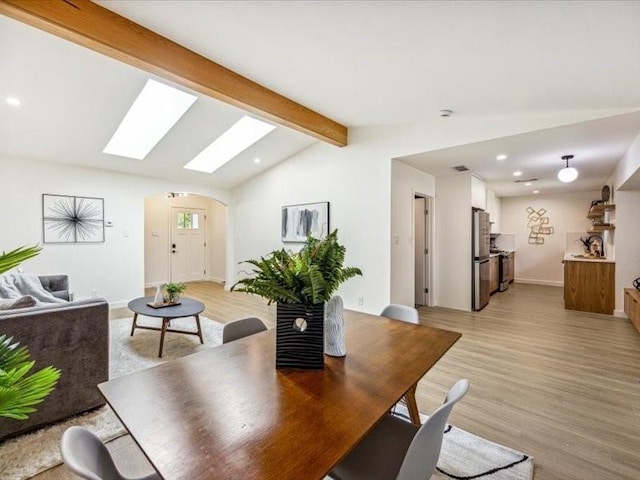 dining space featuring light hardwood / wood-style floors and vaulted ceiling with skylight