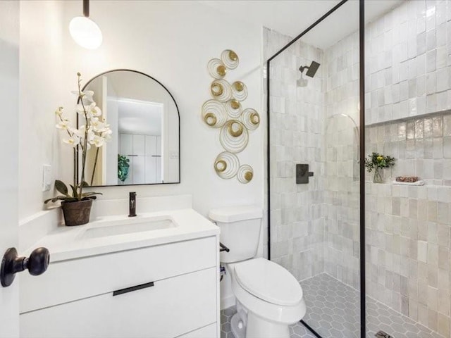 bathroom featuring vanity, toilet, and a tile shower