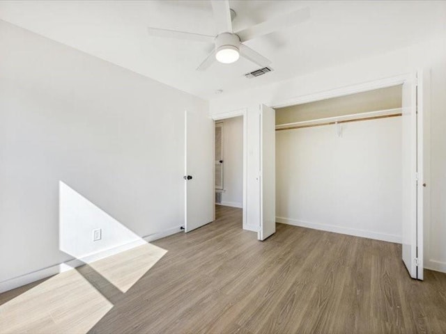 unfurnished bedroom featuring wood-type flooring, a closet, and ceiling fan