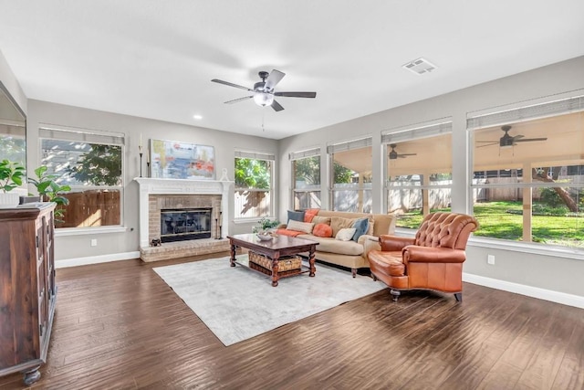 living area featuring dark wood-style flooring, visible vents, a fireplace, and baseboards