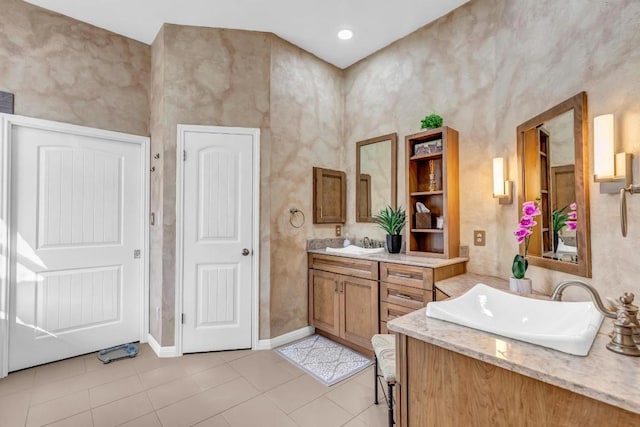 bathroom featuring baseboards, two vanities, a sink, and tile patterned floors