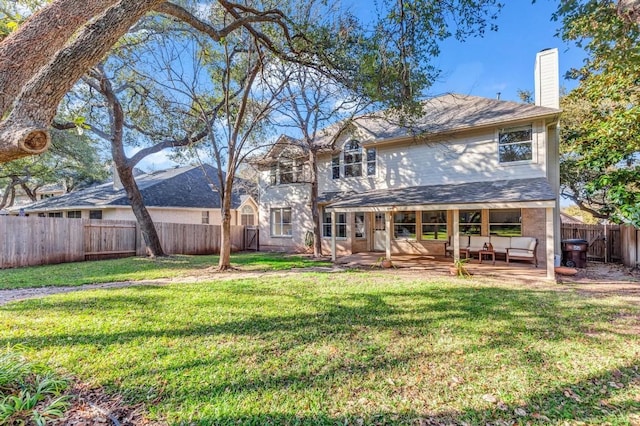 back of property with a fenced backyard, a yard, a chimney, and a patio