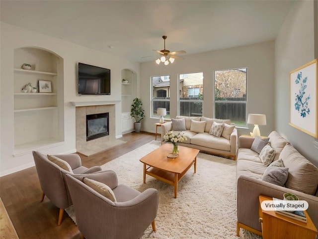 living room featuring light hardwood / wood-style floors, a tile fireplace, and built in features