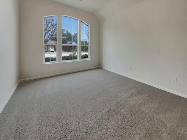 carpeted empty room with vaulted ceiling