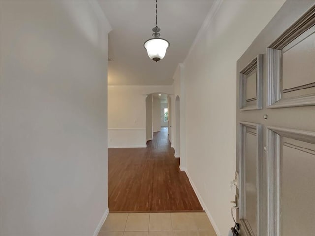 hallway featuring light tile patterned floors and crown molding