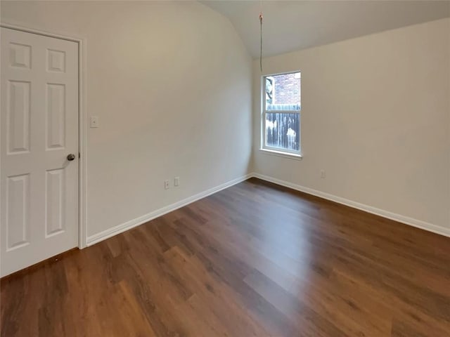 empty room featuring vaulted ceiling and dark hardwood / wood-style floors