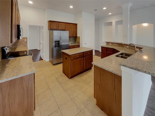 kitchen featuring a kitchen island, sink, light stone counters, kitchen peninsula, and stainless steel appliances