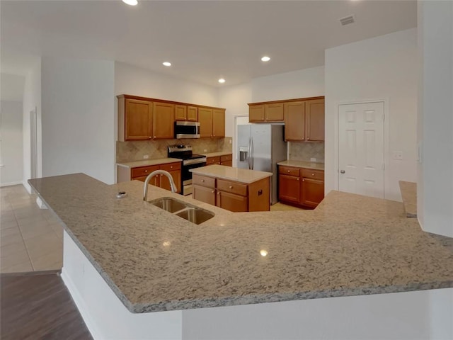 1725 Nelson Ranch Loop, Cedar Park, TX 78613 - kitchen featuring appliances with stainless steel finishes, a sink, light stone countertops, tasteful backsplash, and a center island