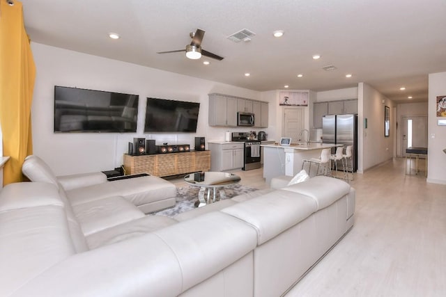 living room with sink, ceiling fan, and light hardwood / wood-style flooring