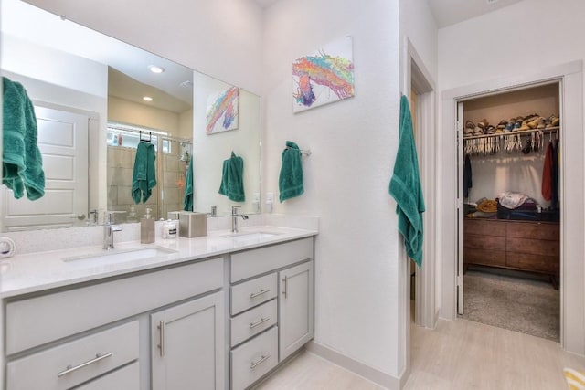 bathroom featuring a spacious closet, a stall shower, double vanity, and a sink