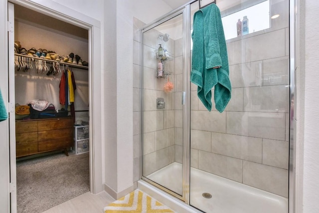 full bathroom with a spacious closet and a stall shower