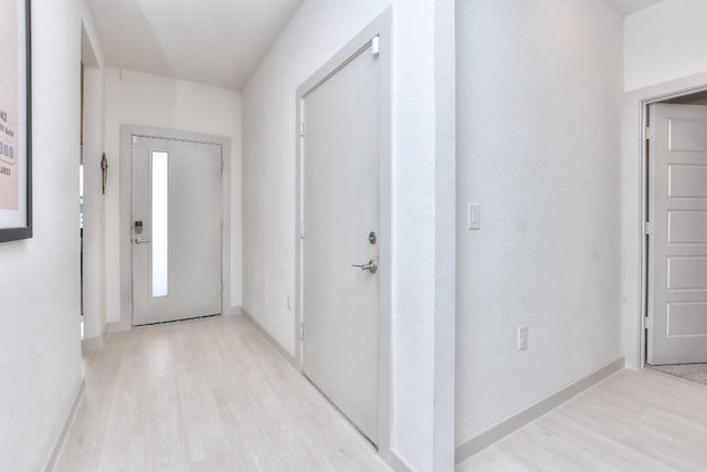 corridor with baseboards and light wood-style flooring