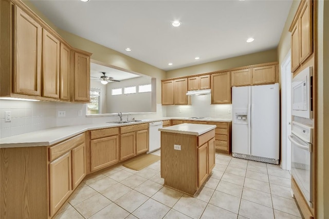 kitchen featuring white appliances, sink, a kitchen island, and backsplash