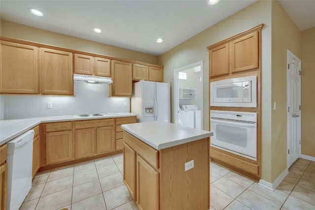 kitchen with light tile patterned floors, white appliances, washer and clothes dryer, backsplash, and a kitchen island