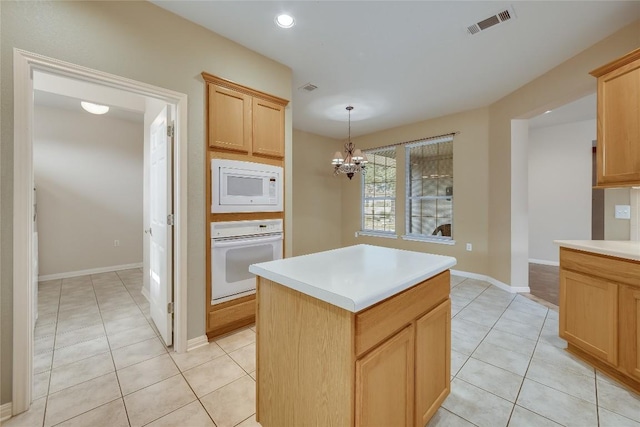 kitchen featuring light tile patterned flooring, white appliances, decorative light fixtures, and a center island