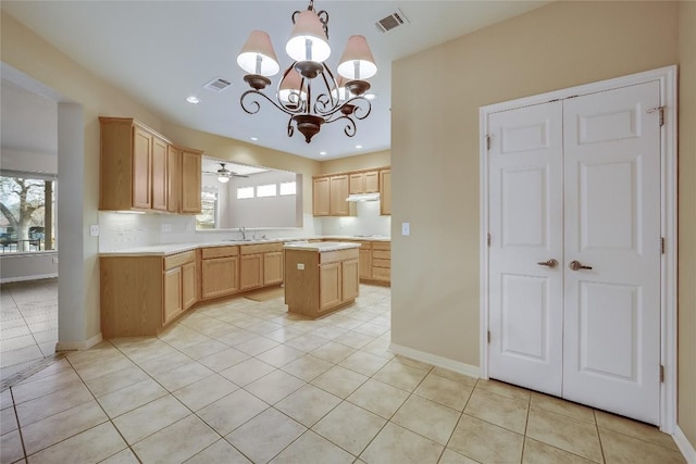 kitchen featuring light tile patterned flooring, light brown cabinetry, sink, a center island, and pendant lighting