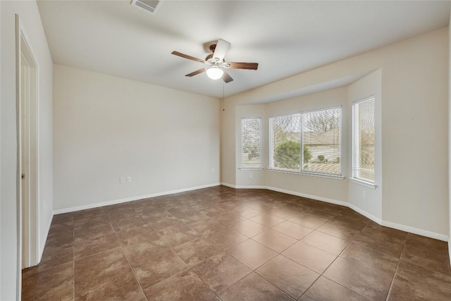 empty room with ceiling fan and dark tile patterned floors