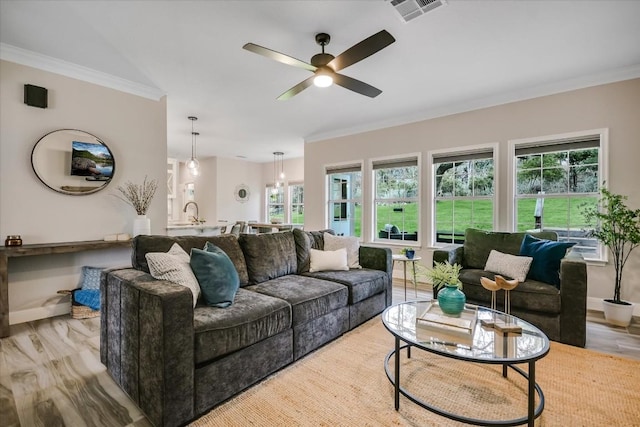 living room with crown molding, plenty of natural light, and light hardwood / wood-style flooring