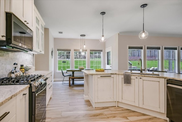 kitchen with gas range, light stone countertops, tasteful backsplash, and pendant lighting