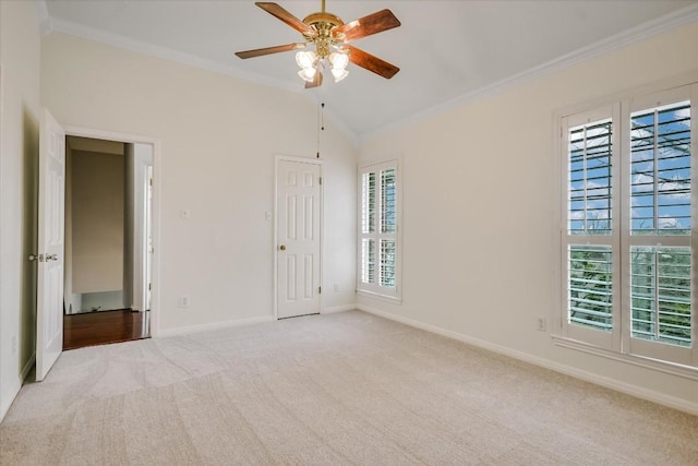 spare room featuring crown molding, vaulted ceiling, light carpet, and ceiling fan