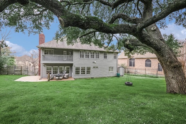 rear view of property featuring a balcony, a yard, and a patio