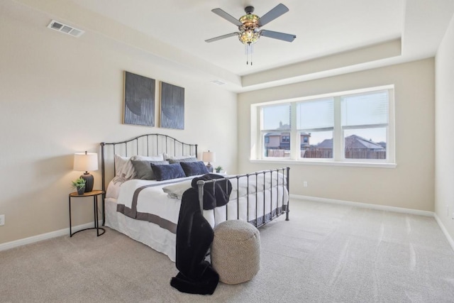 carpeted bedroom featuring a raised ceiling and ceiling fan