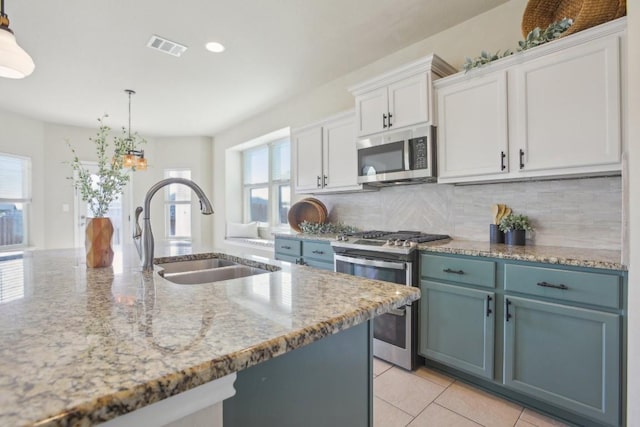 kitchen featuring stainless steel appliances, white cabinetry, sink, and decorative light fixtures