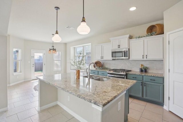 kitchen featuring sink, white cabinetry, light stone counters, decorative light fixtures, and appliances with stainless steel finishes