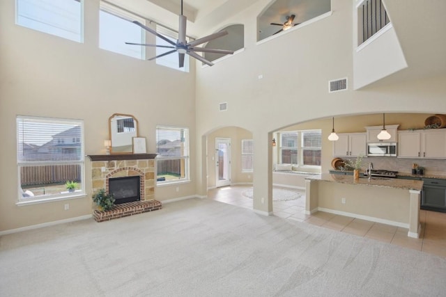 living room featuring a fireplace, light colored carpet, and ceiling fan