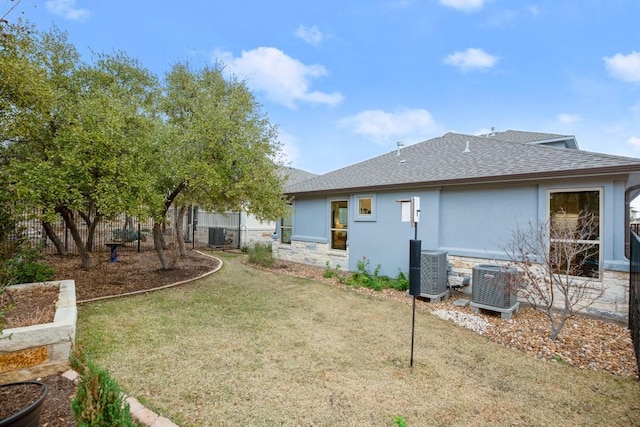 rear view of property featuring central AC unit and a lawn