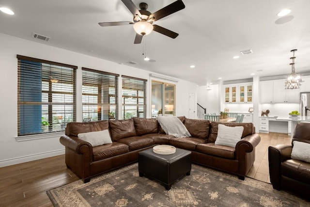 living room featuring ceiling fan with notable chandelier and dark hardwood / wood-style floors