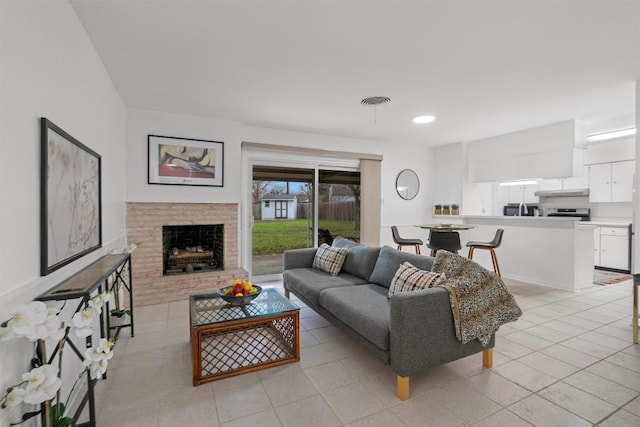 living room with a brick fireplace and light tile patterned floors