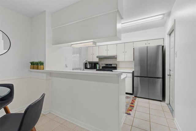 kitchen featuring light tile patterned floors, a kitchen breakfast bar, kitchen peninsula, stainless steel appliances, and white cabinets