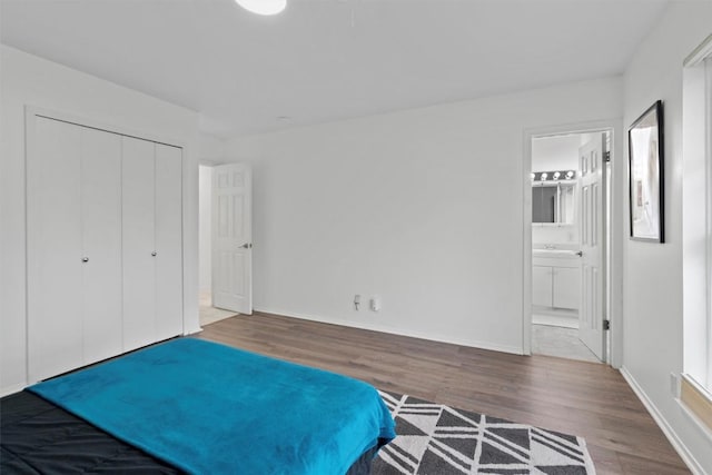 unfurnished bedroom featuring ensuite bath, hardwood / wood-style floors, and a closet