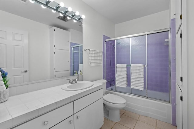 full bathroom with bath / shower combo with glass door, vanity, tile patterned floors, and toilet