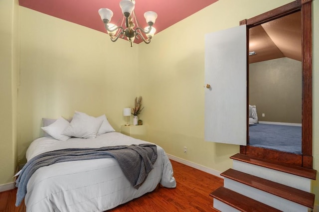 bedroom with vaulted ceiling, hardwood / wood-style floors, and an inviting chandelier