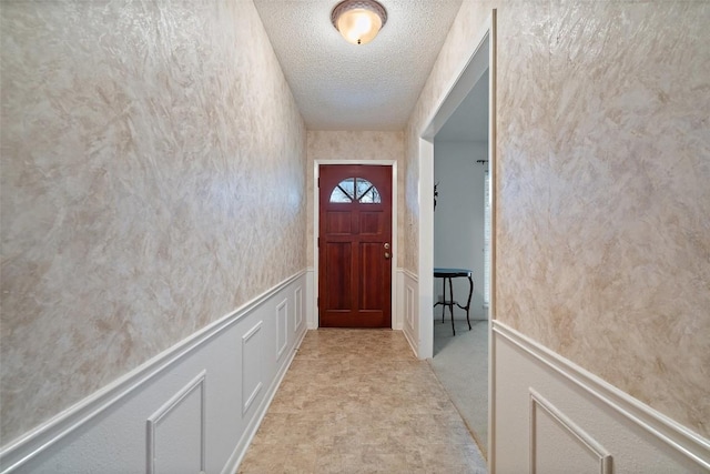 doorway featuring light carpet and a textured ceiling