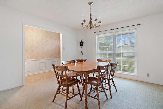 dining room featuring light colored carpet, a chandelier, and a textured ceiling