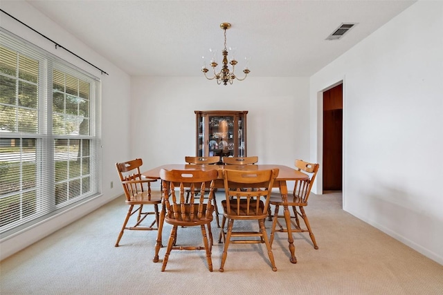 dining area featuring a notable chandelier and light colored carpet