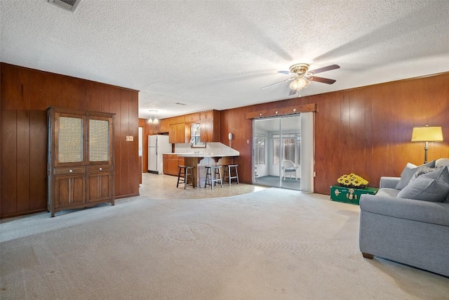 living room with light colored carpet, a textured ceiling, and wood walls