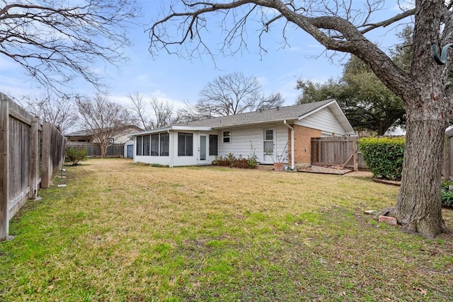 back of property with a lawn and a sunroom