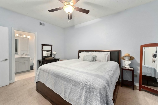 bedroom with light carpet, ceiling fan, and ensuite bath