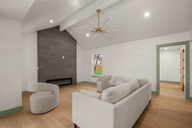 living room with vaulted ceiling with beams, a fireplace, and light wood-type flooring