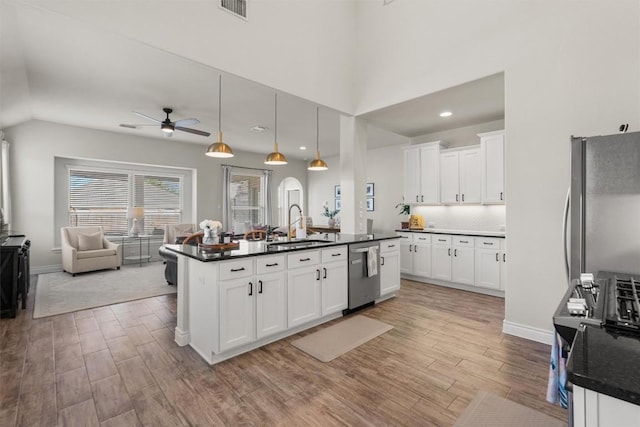 kitchen with appliances with stainless steel finishes, pendant lighting, sink, white cabinets, and a center island with sink